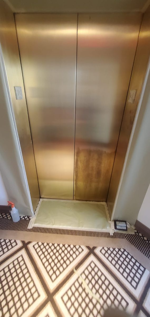 The same brass doors part-way through restoration, most of the surface back to a bright even gold