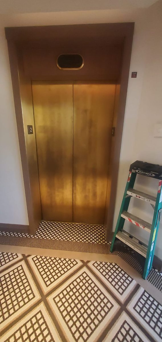 Brass elevator doors darkened by oxidation and water streaking, before restoration